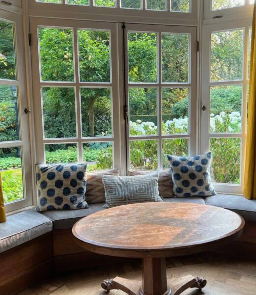 Bay aluminium windows with classic grid-style frames and a built-in bench offering a cozy garden view.