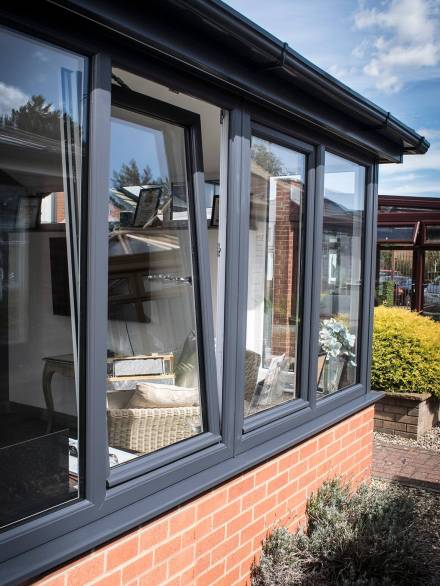 Flush Tilt & Turn Windows with a dark aluminum frame, perfectly complementing a brick facade.