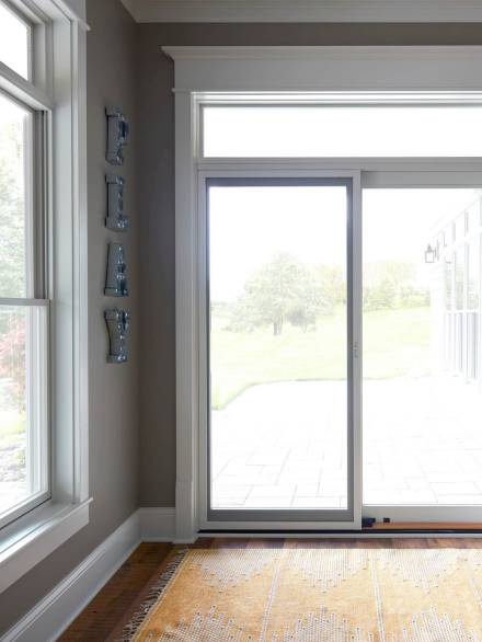 A bright indoor space featuring a minimalist sliding patio door with a clean white aluminum frame, offering a clear view of the outdoor garden area.