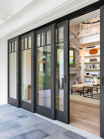 Black-framed multi-panel french doors with large glass inserts, seamlessly connecting a cozy living space with a covered outdoor patio