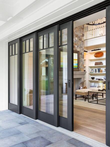 Black-framed multi-panel french doors with large glass inserts, seamlessly connecting a cozy living space with a covered outdoor patio